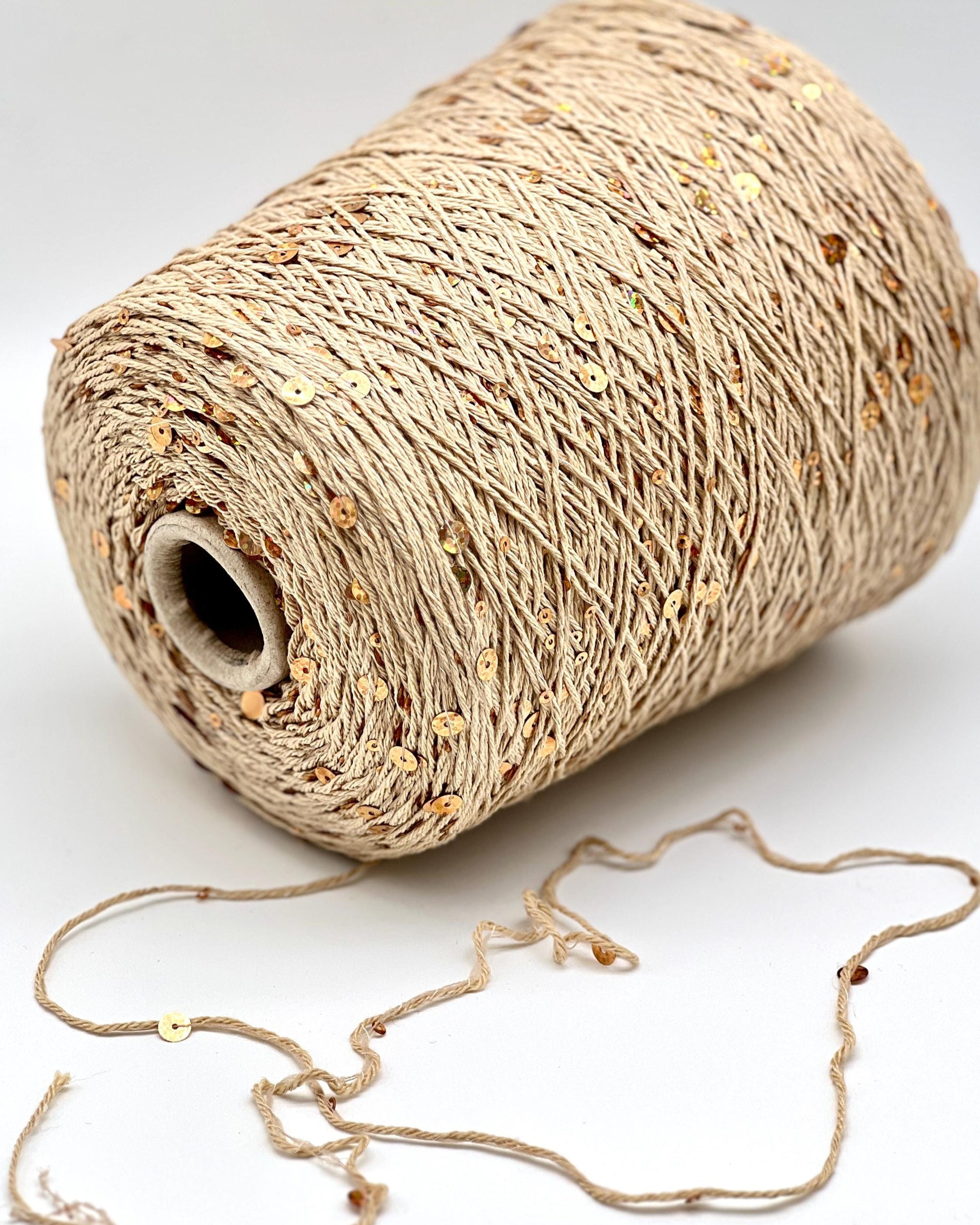 Spool of beige thread with a small piece unwound on a white background