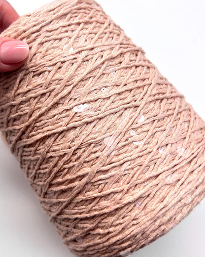 Ball of pink yarn held by a hand on a white background