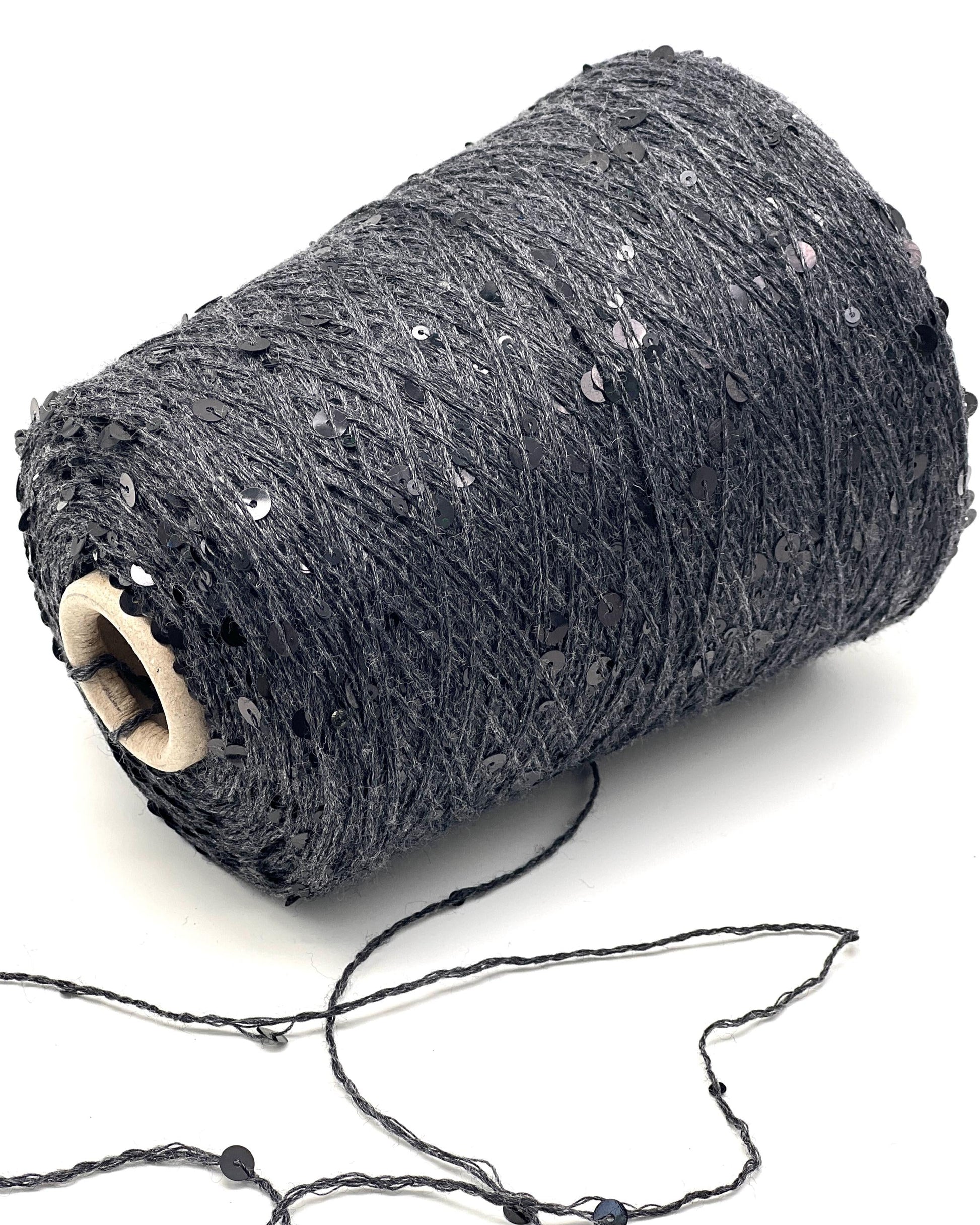 Roll of dark gray yarn with sequins on a white background