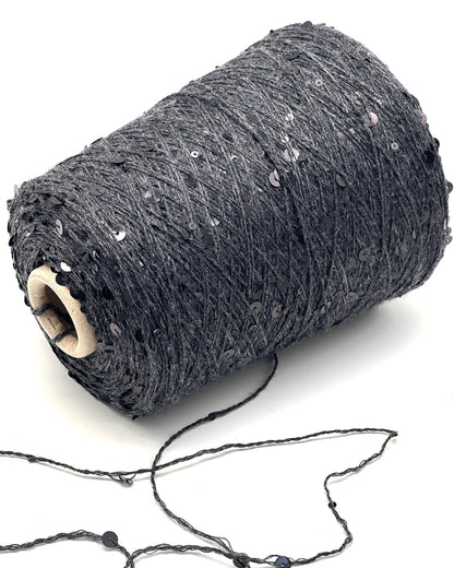 Roll of dark gray yarn with sequins on a white background