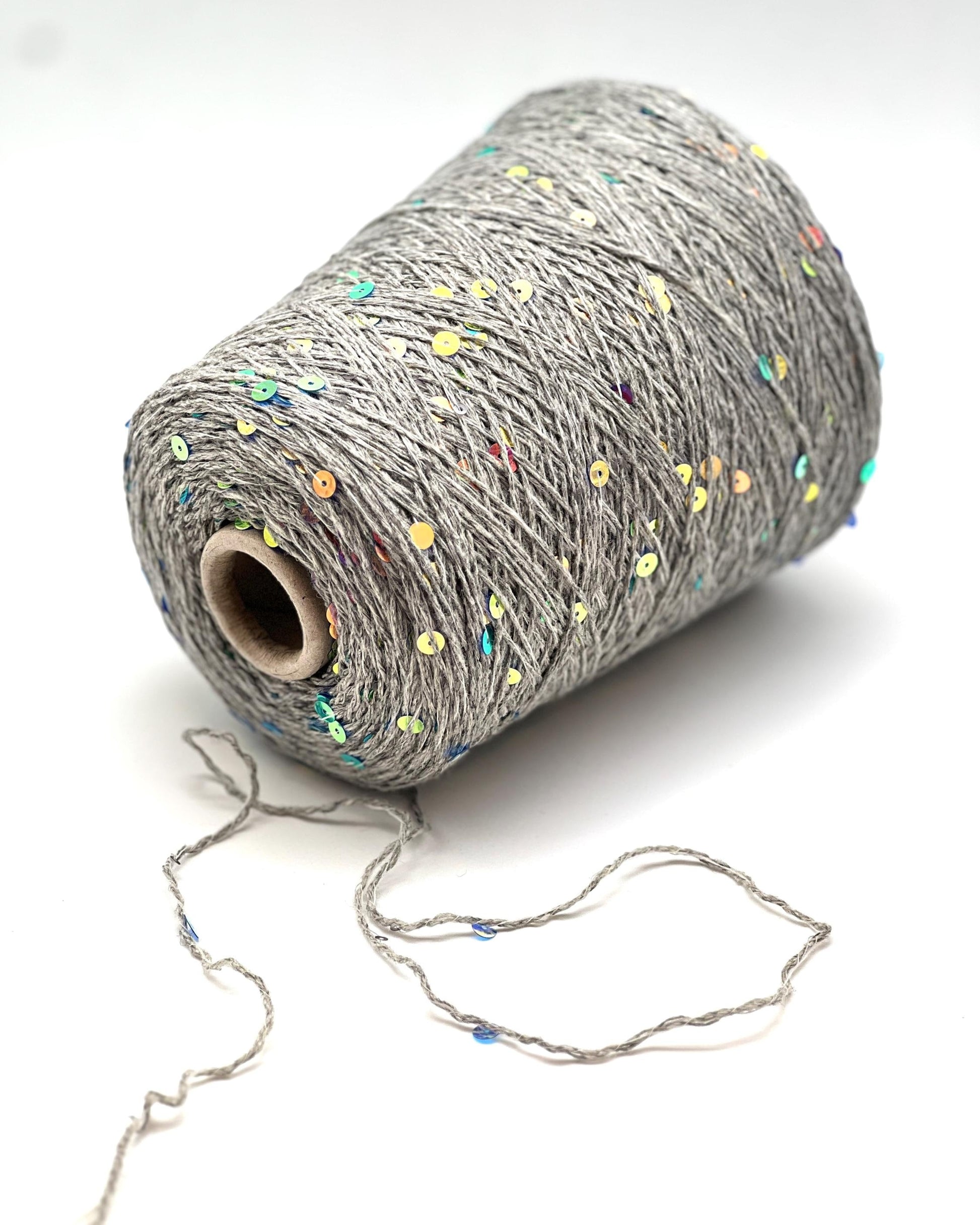Spool of gray yarn with colorful specks on a white background