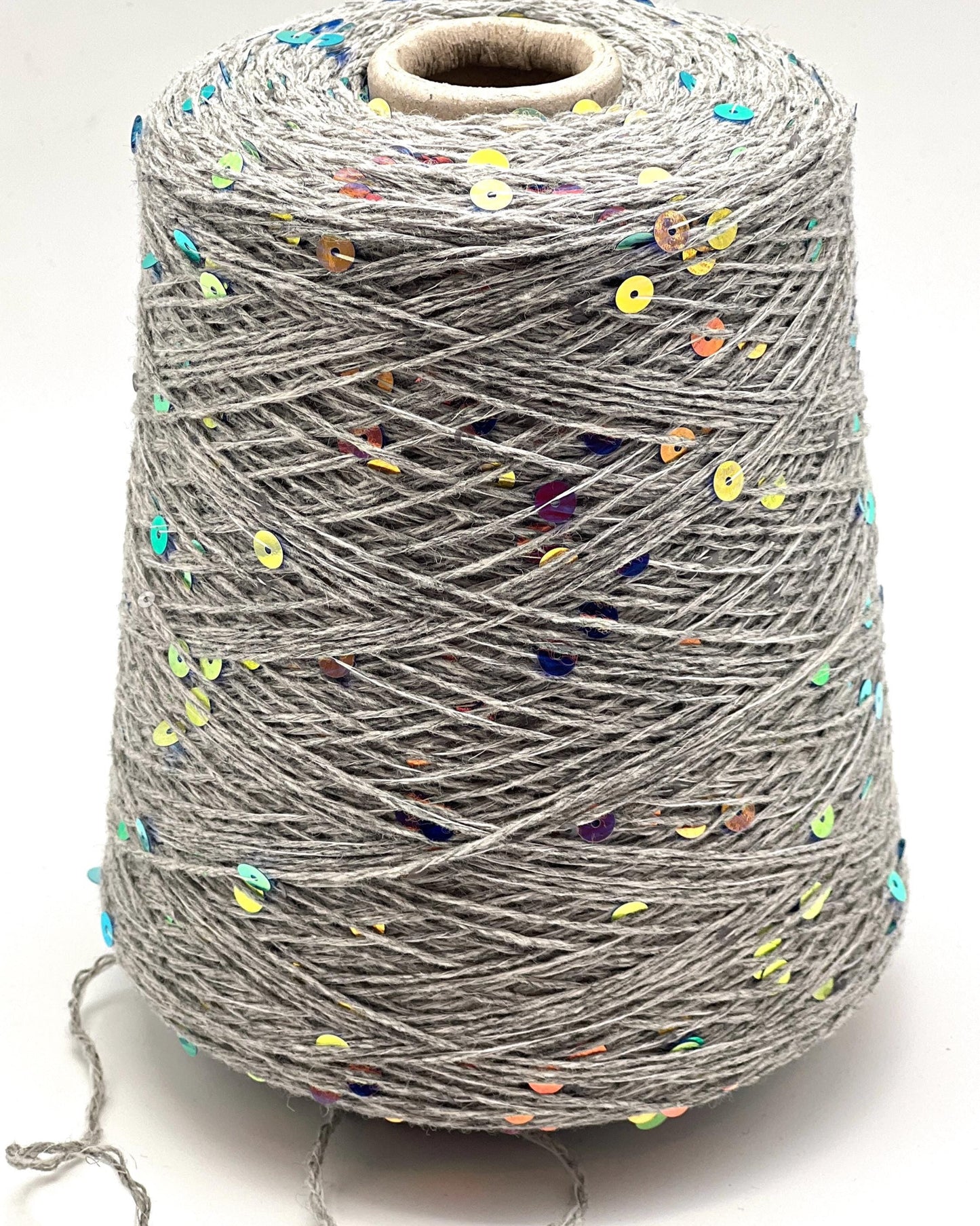 Spool of gray yarn with colorful specks on a white background