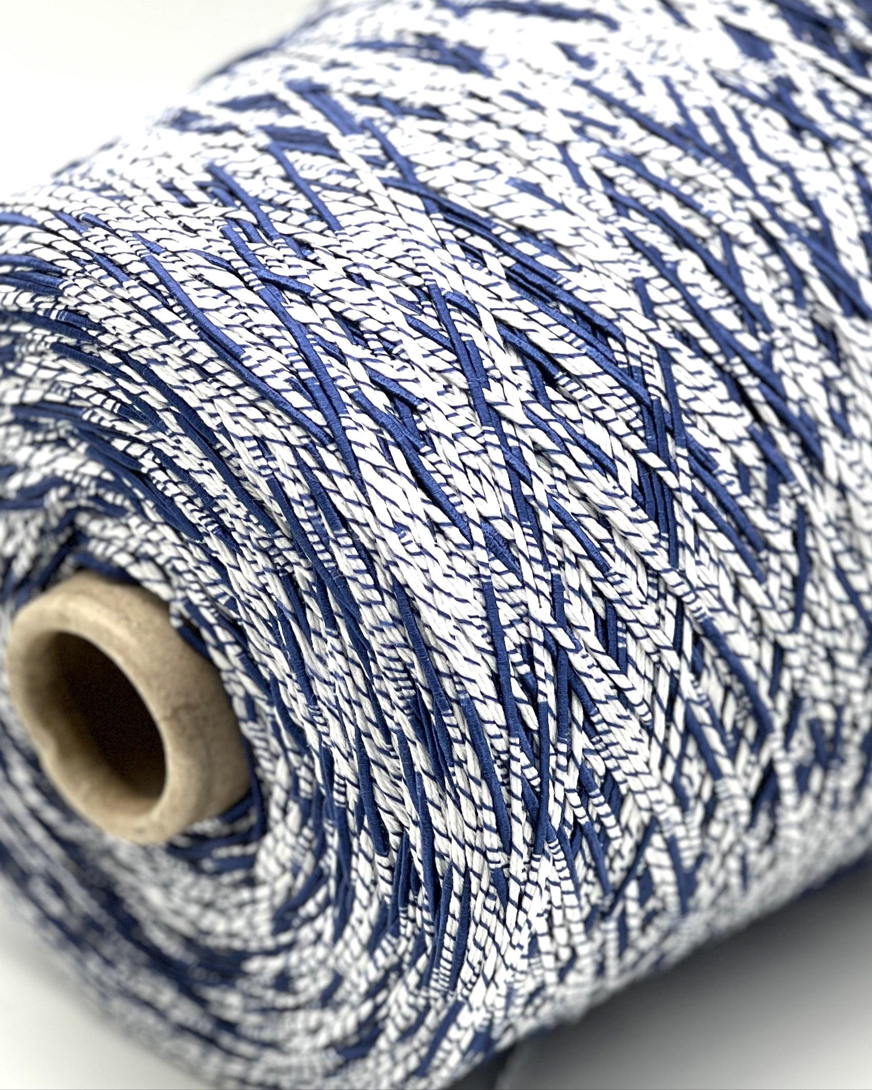 Close-up of a spool of blue and white yarn on a light background