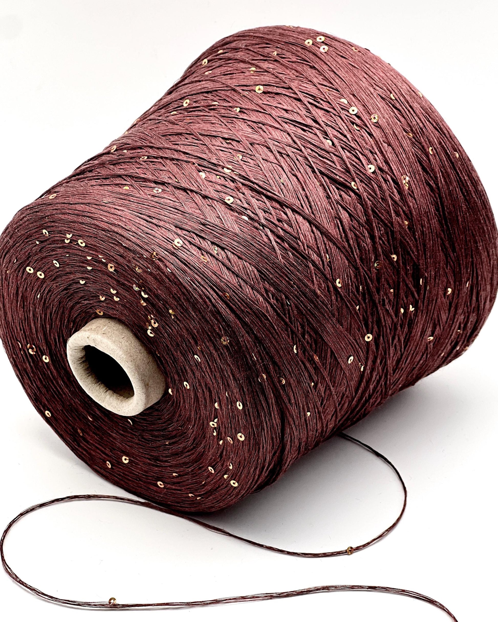Spool of brown thread with glitter on a white background