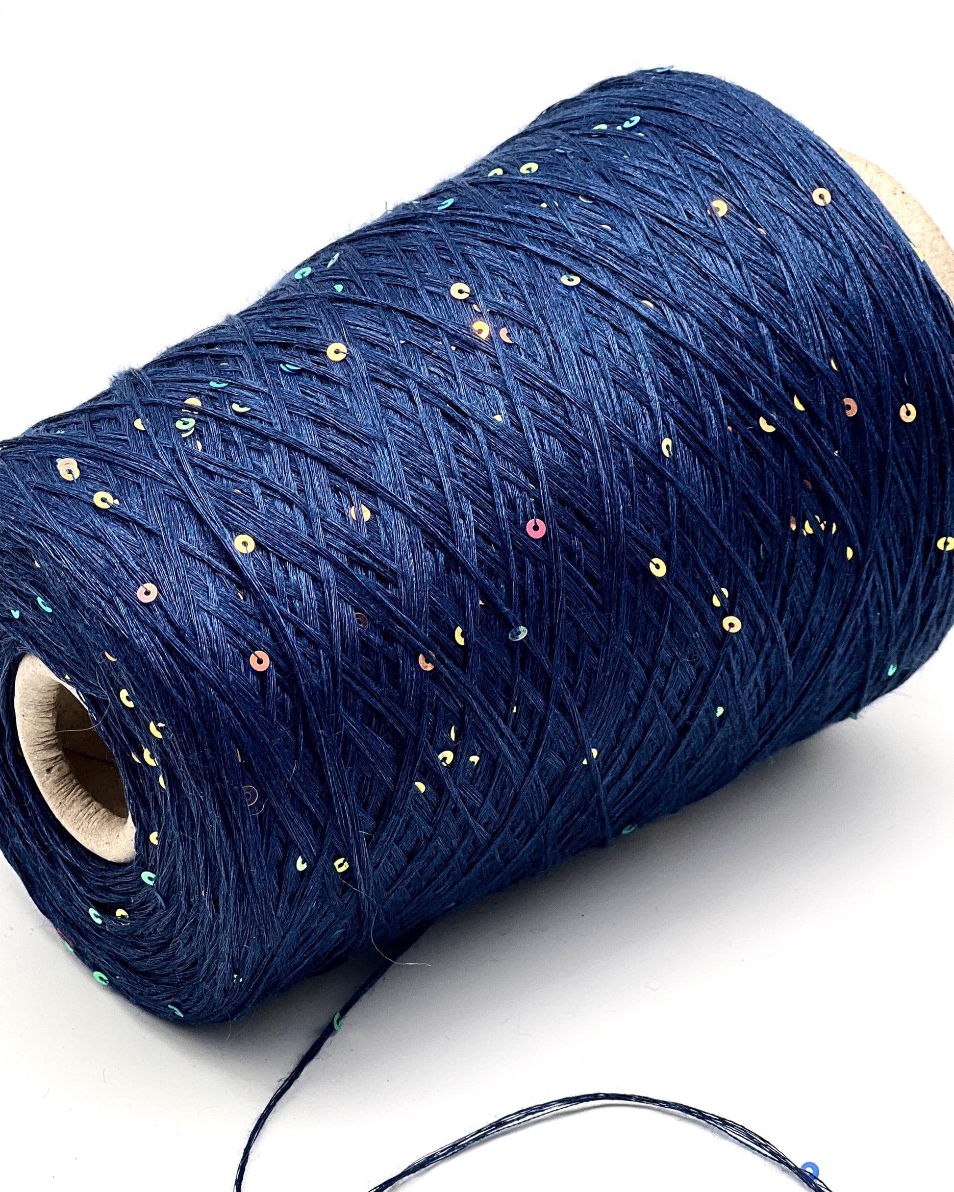Roll of blue thread with sequins on a white background