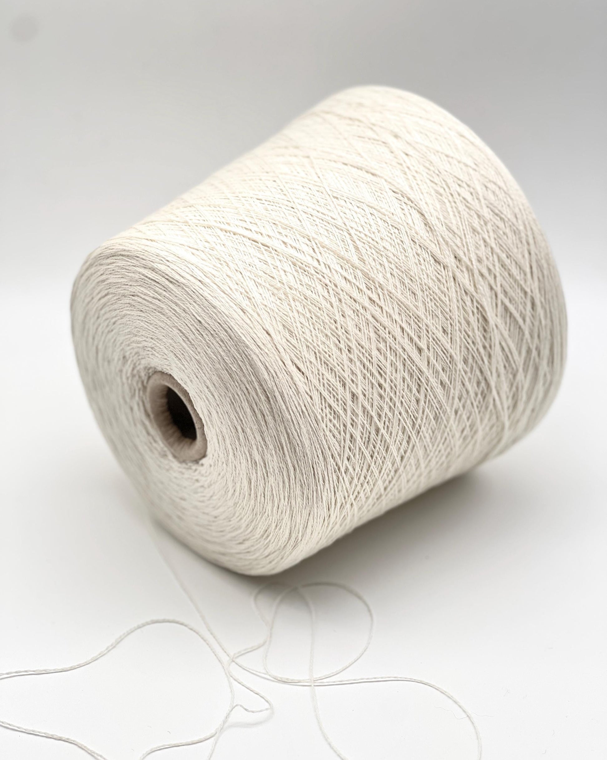 Large spool of white yarn on a light gray background
