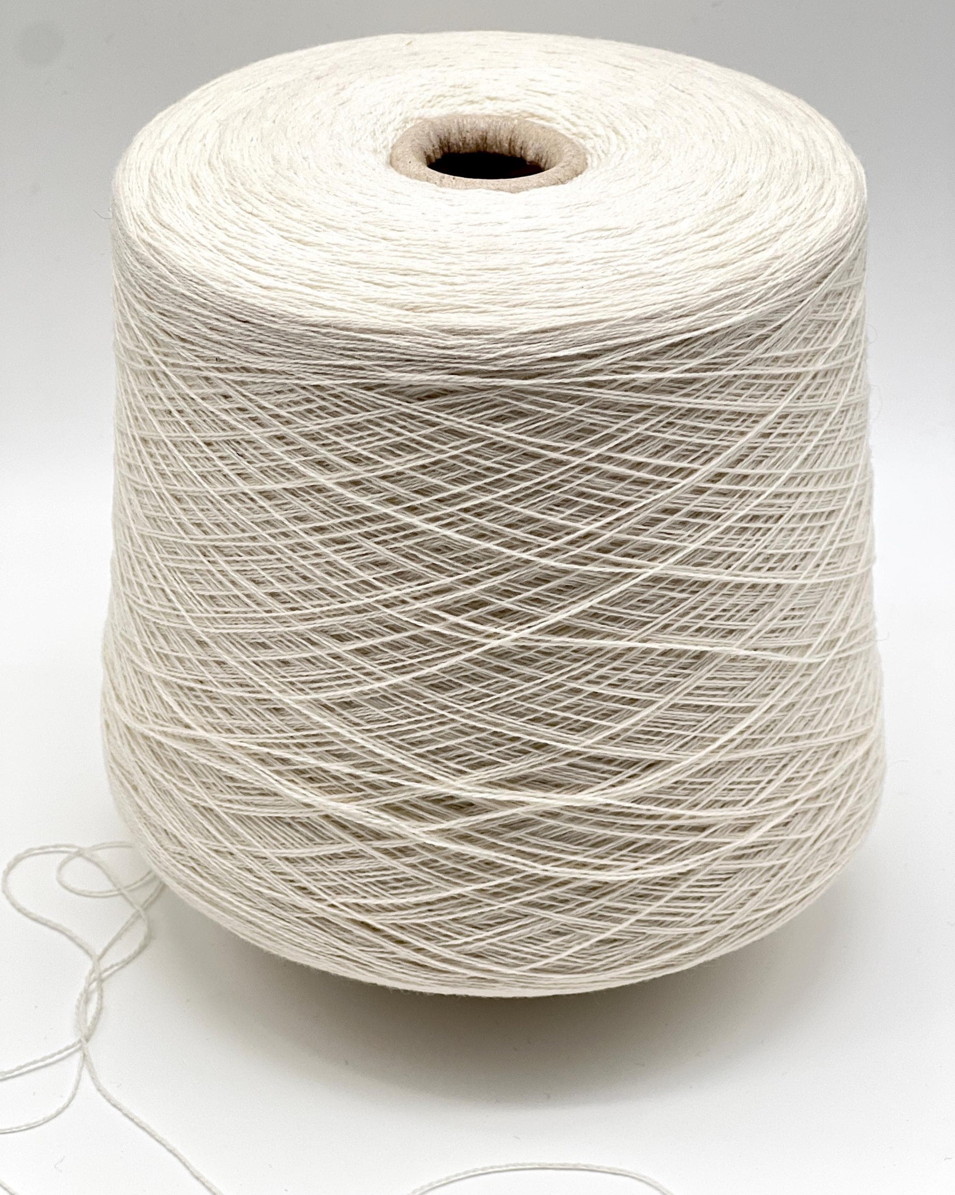 Spool of white yarn on a light gray background