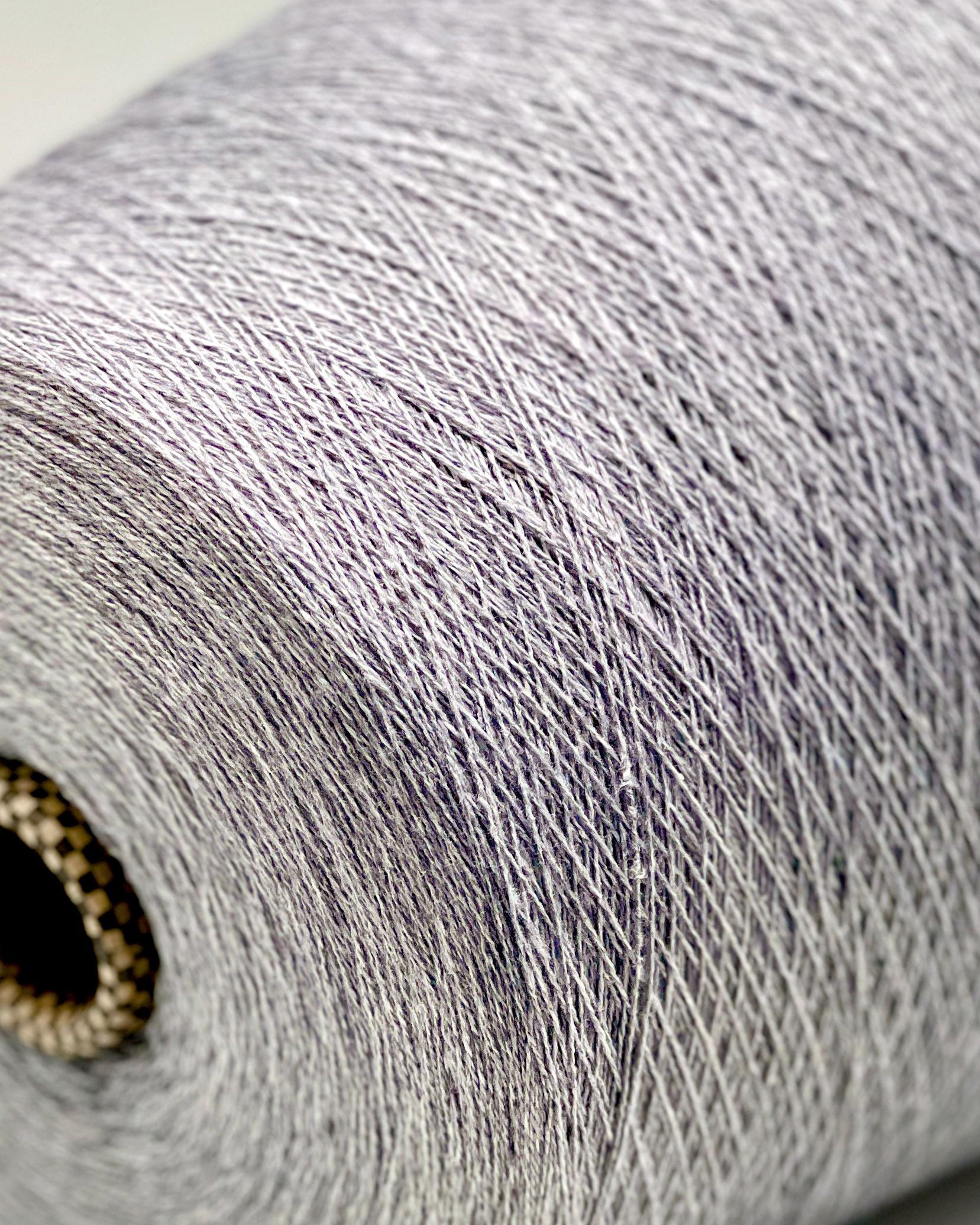 Close-up of a roll of gray yarn with a visible brand logo.