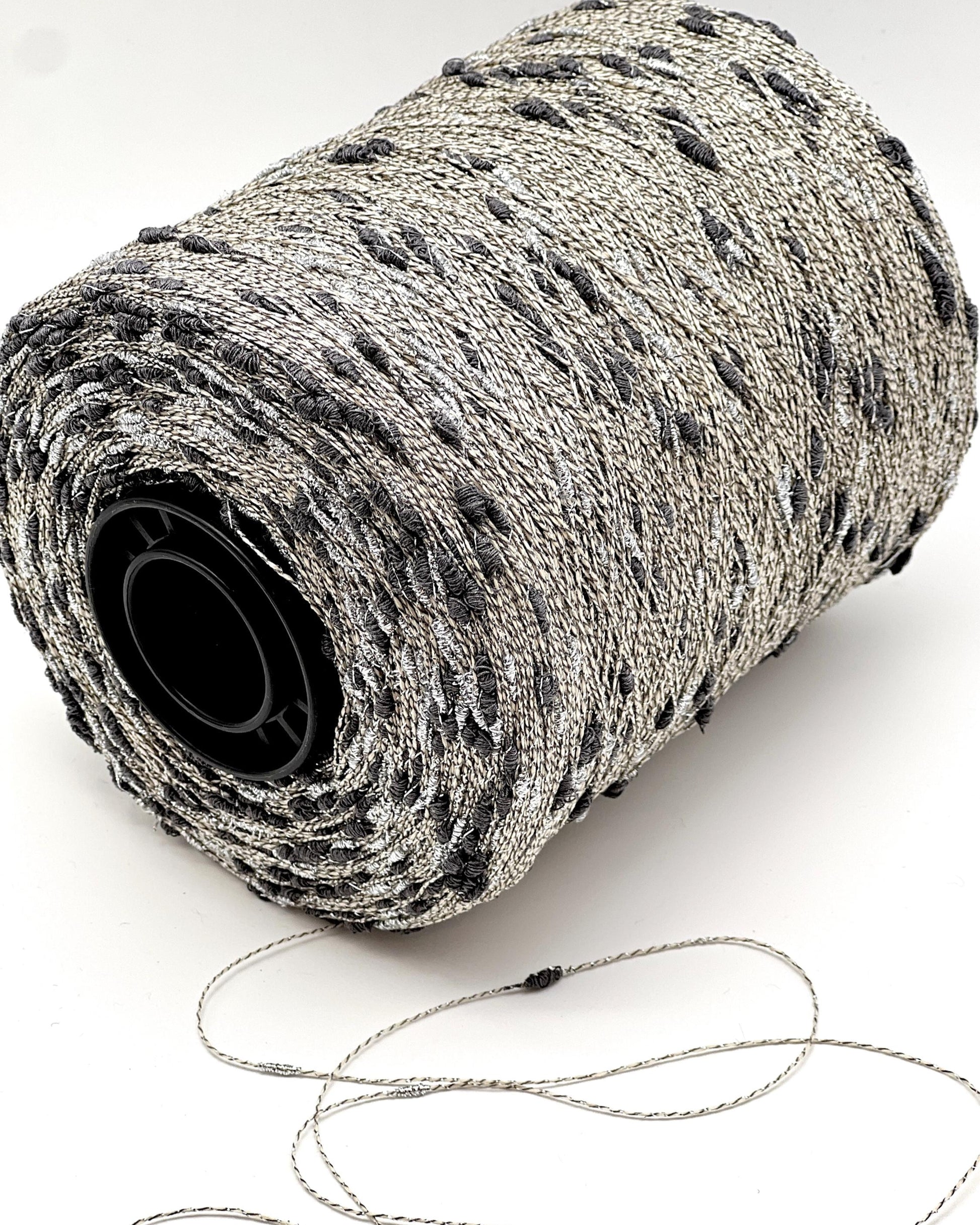 Roll of gray yarn with a black core on a white background