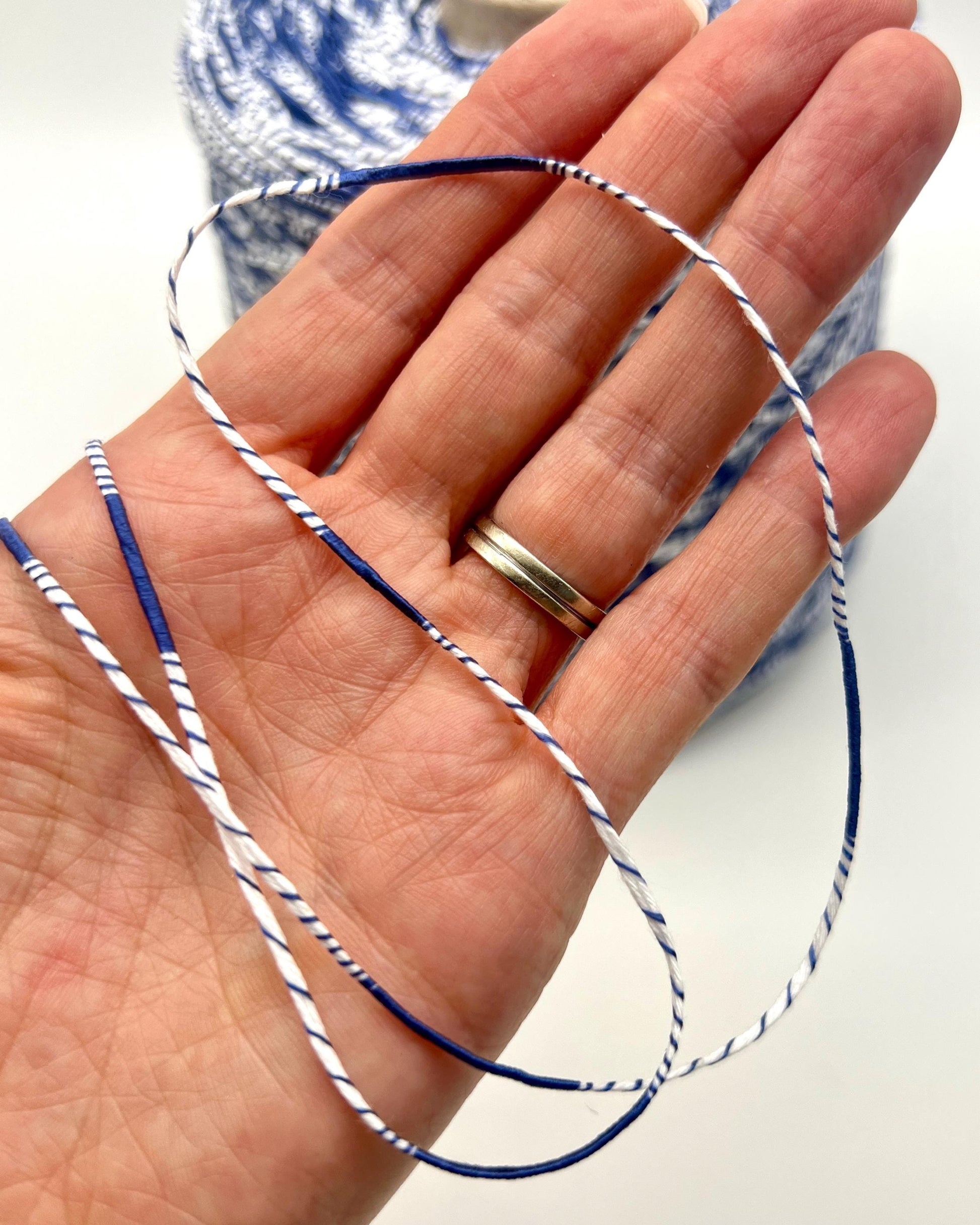 Hand holding blue and white string with spool in background
