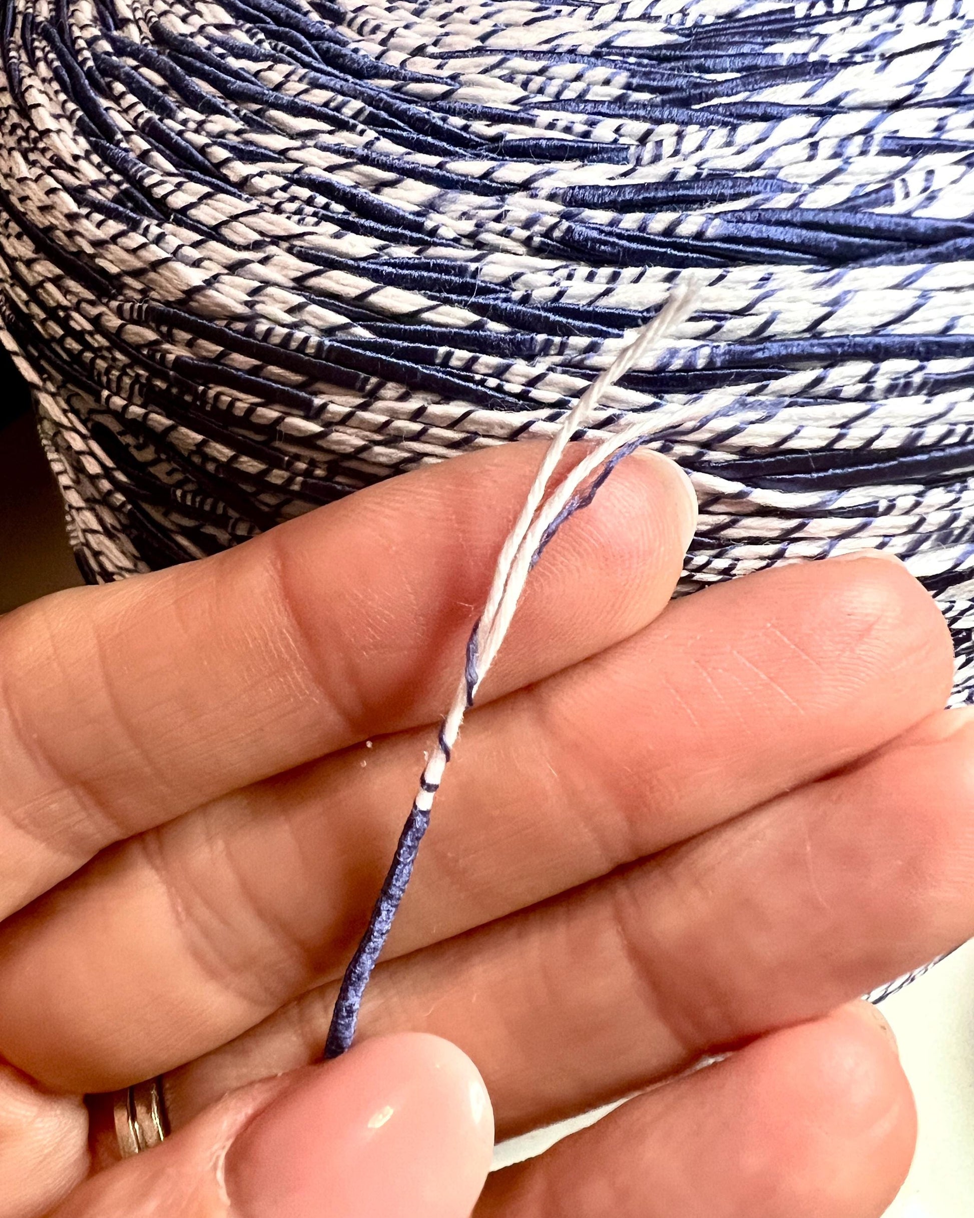 Close-up of hands holding a ball of blue and white yarn.