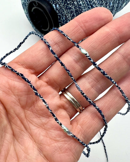 Hand holding a blue and white braided cord with a blurred background