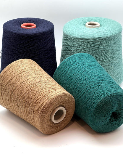 Four spools of yarn in navy, beige, green, and teal on a white background