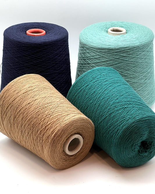 Four spools of yarn in navy, beige, green, and teal on a white background