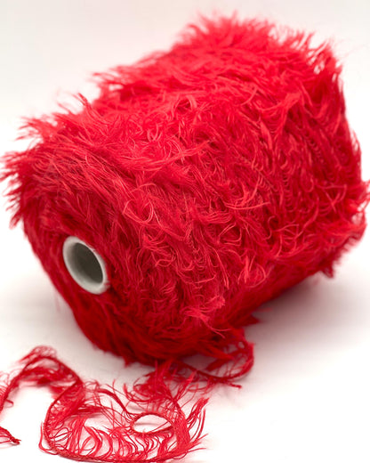 Red yarn ball with loose strands on a white background