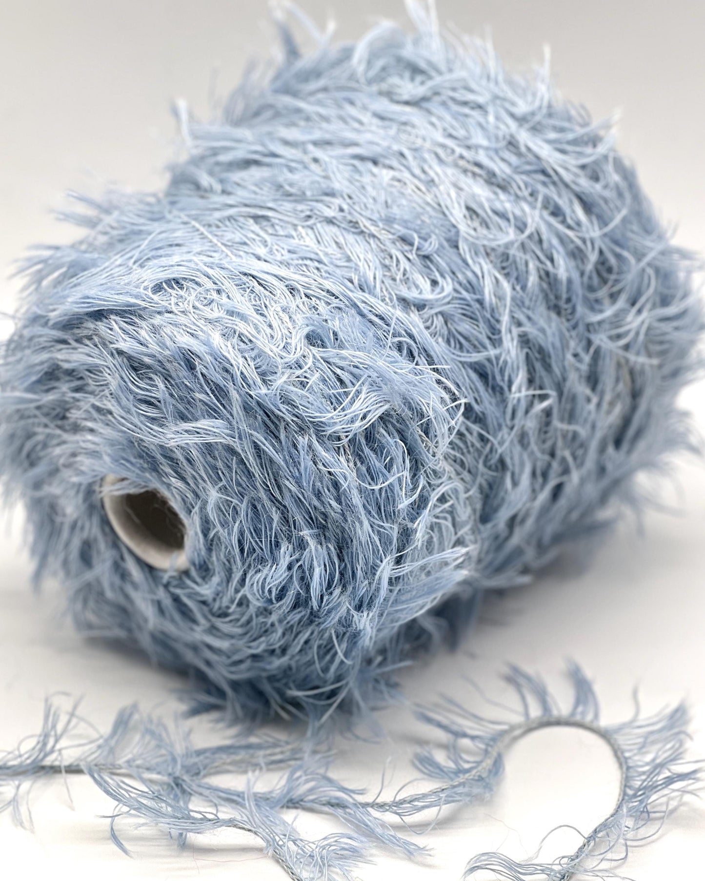 Blue yarn ball with loose strands on a white background