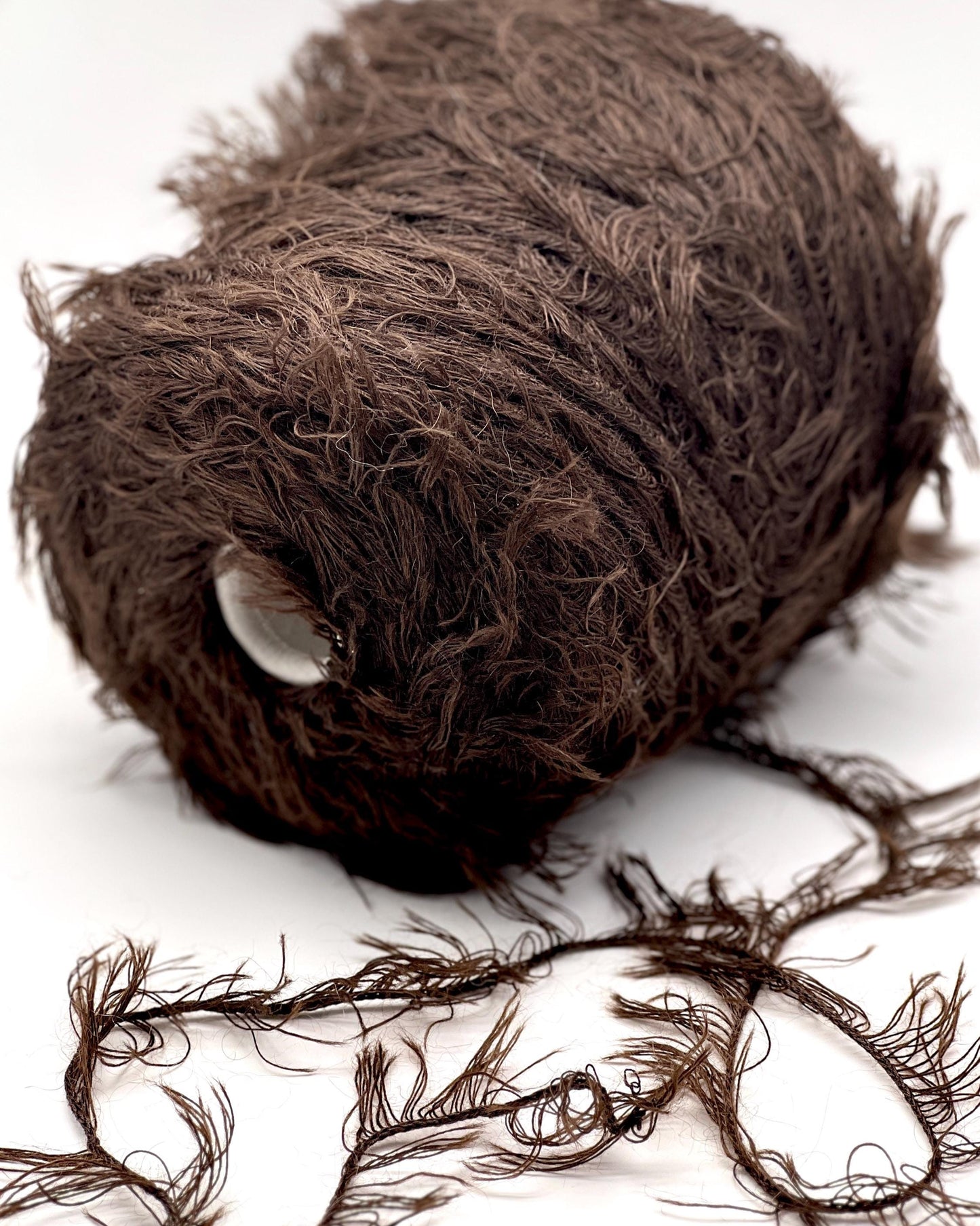 Brown yarn ball with some strands on a white background