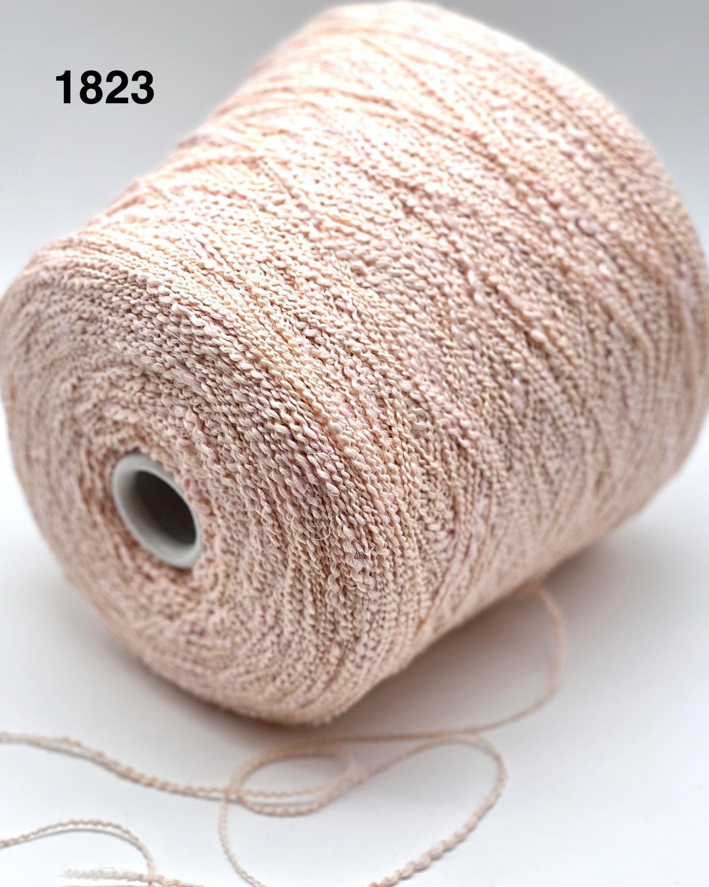 Spool of beige yarn on a white background