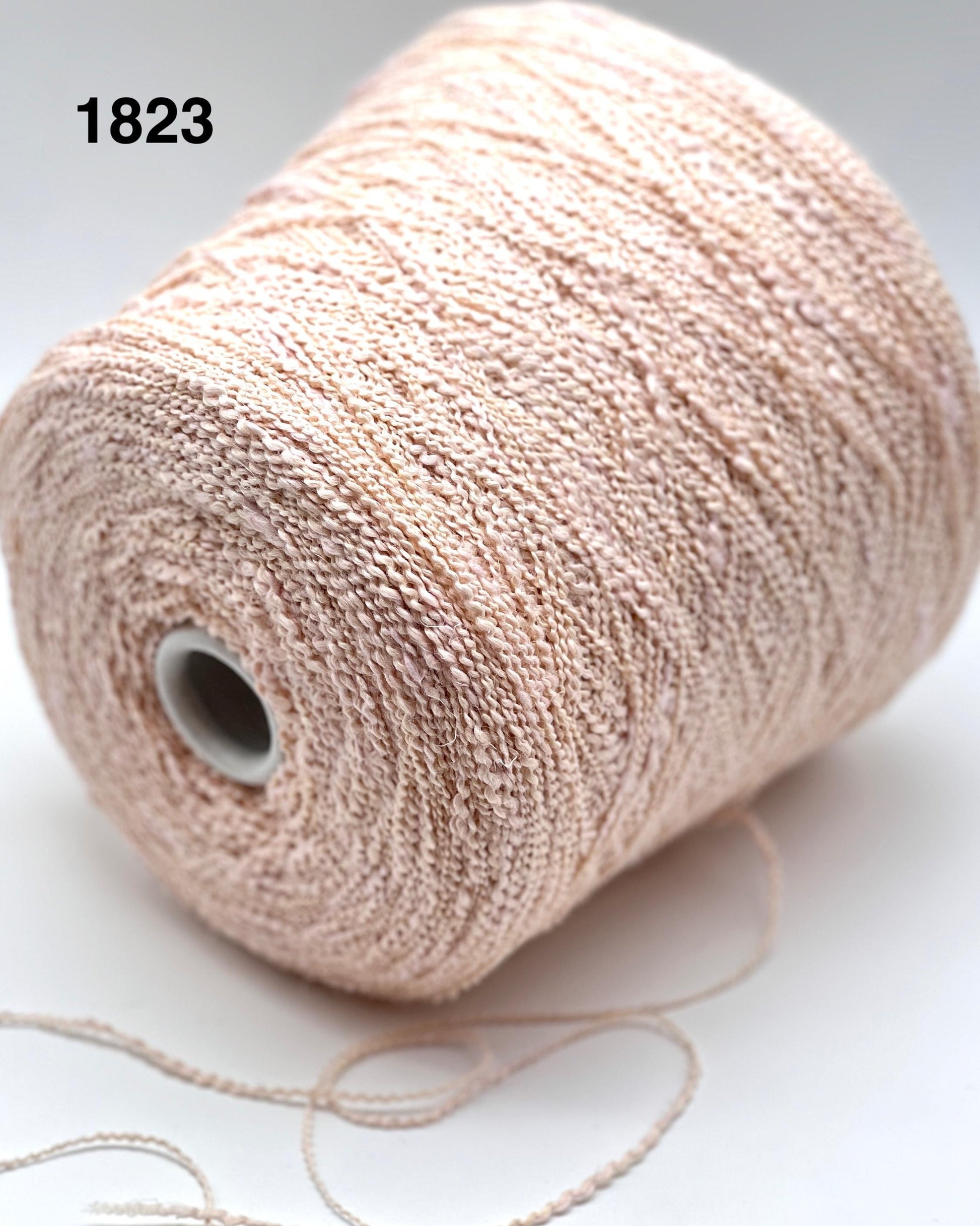 Spool of beige yarn on a white background