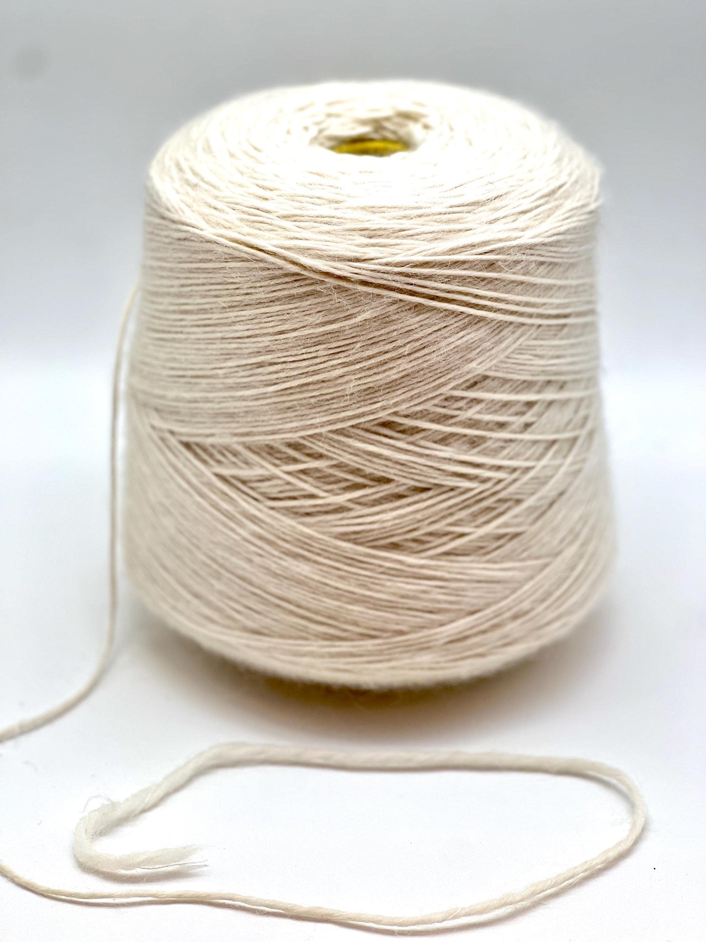 Spool of beige yarn on a white background