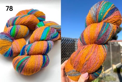 Colorful skeins of yarn on a white background and held in a hand with a blue sky and trees in the background.