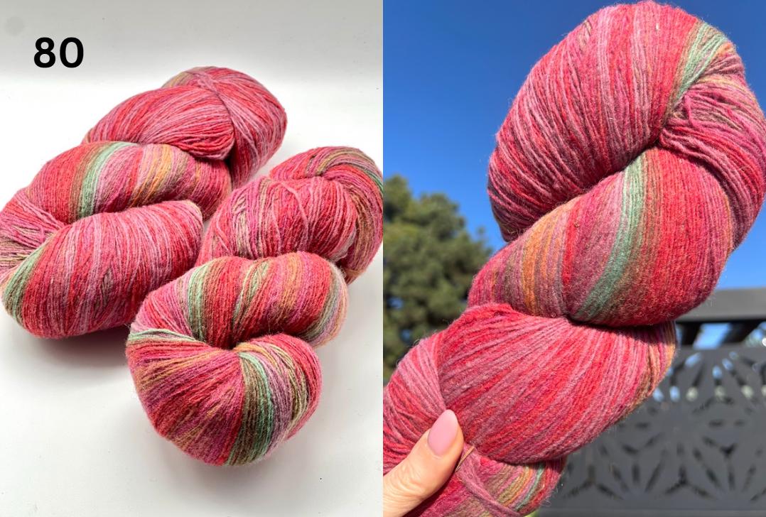 Red and green striped yarn skeins on a white background with a blue sky and trees in the background.
