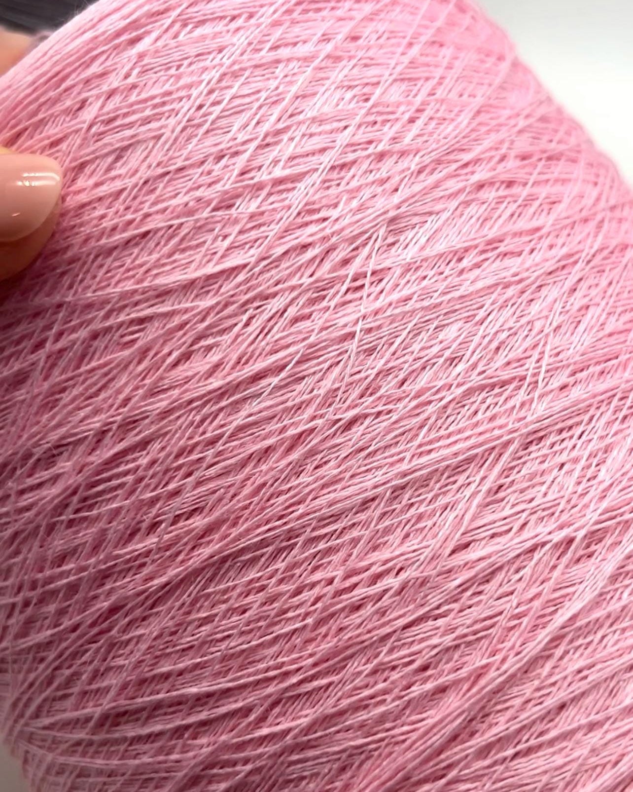 Close-up of a ball of pink yarn held by a hand.