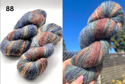 Multicolored skein of yarn on a white background and held in hand with outdoor background.