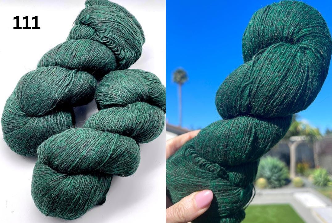 Green yarn skein held by a hand with a blurred outdoor background