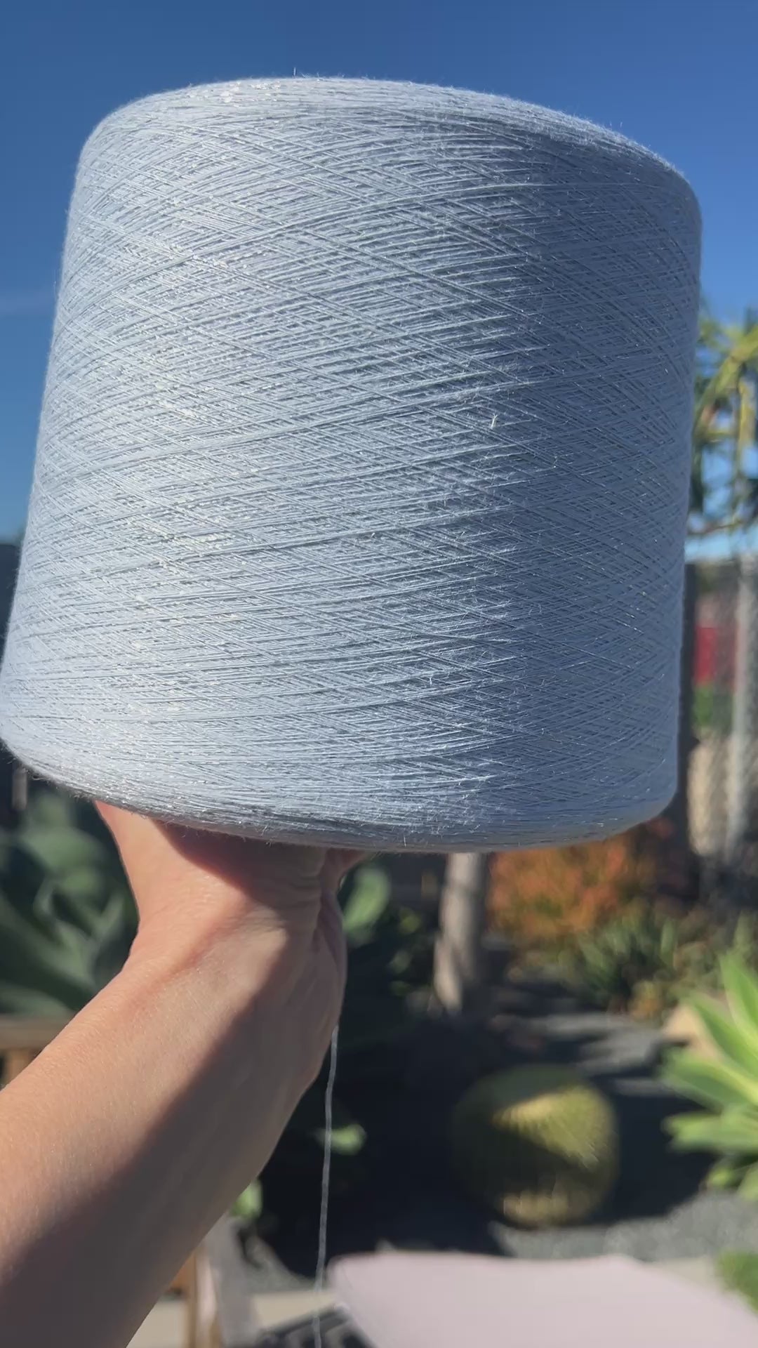 A luxurious cone of Pecci Filati SHIMMER yarn, a modern 50% Cotton, 25% Linen, 14% Polyester, and 12% Polyamide (Lurex) blend. The image showcases the refined metallic glow and delicate texture of this 3400m/100g Italian extrafine yarn, ideal for high-end blending. Authentic luxury fiber available at iDOKNiT.com.