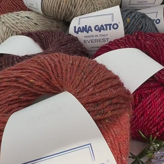Close-up of iDOKNiT Lana Gatto EVEREST tweed yarn, showing the rustic texture of the Merino and Viscose blend with signature colorful neps in a 50g ball.