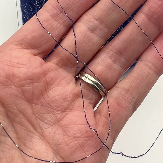 A luxurious cone of Pecci Filati SHIMMER yarn, a modern 50% Cotton, 25% Linen, 14% Polyester, and 12% Polyamide (Lurex) blend. The image showcases the refined metallic glow and delicate texture of this 3400m/100g Italian extrafine yarn, ideal for high-end blending. Authentic luxury fiber available at iDOKNiT.com.