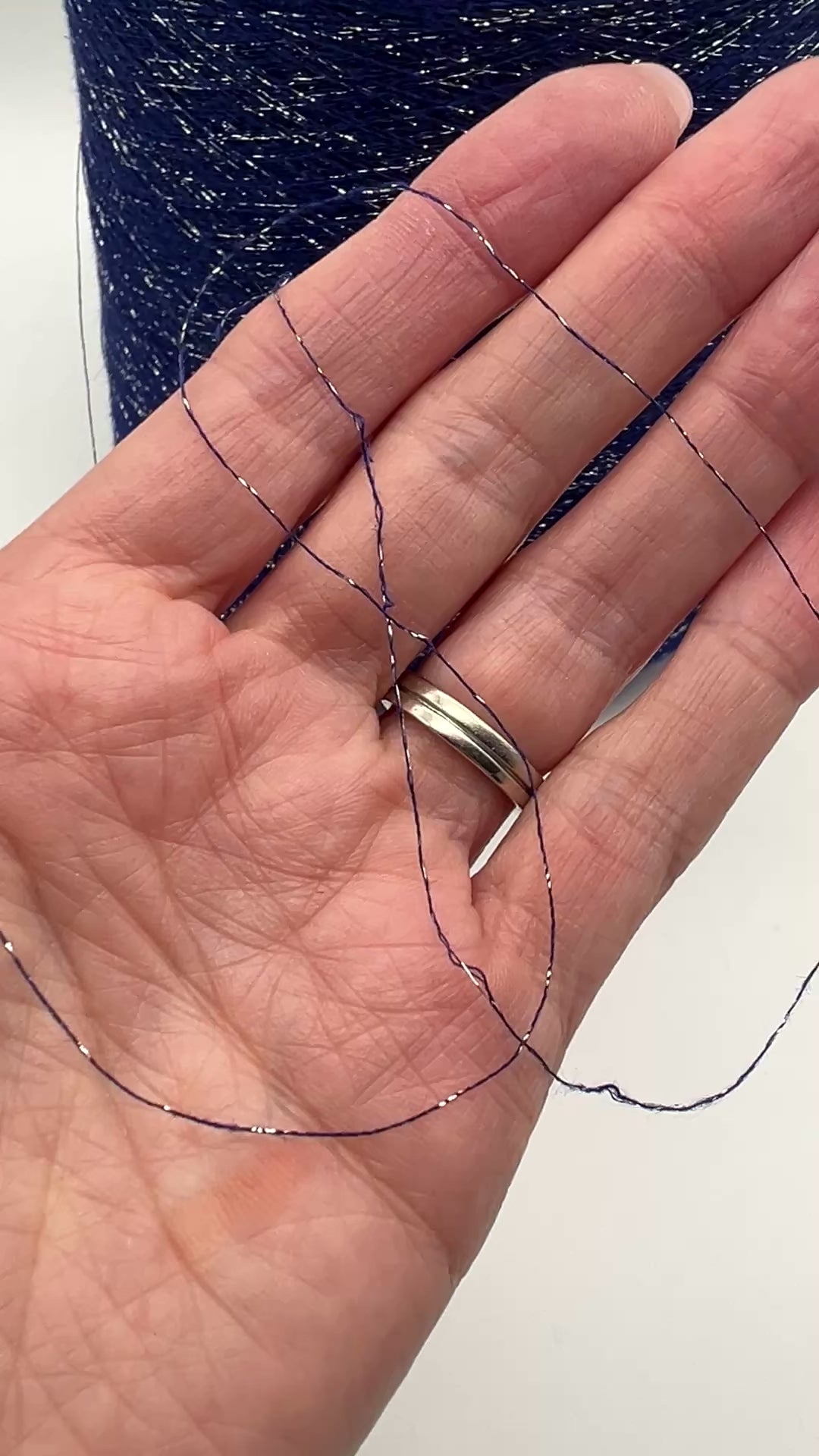 A luxurious cone of Pecci Filati SHIMMER yarn, a modern 50% Cotton, 25% Linen, 14% Polyester, and 12% Polyamide (Lurex) blend. The image showcases the refined metallic glow and delicate texture of this 3400m/100g Italian extrafine yarn, ideal for high-end blending. Authentic luxury fiber available at iDOKNiT.com.