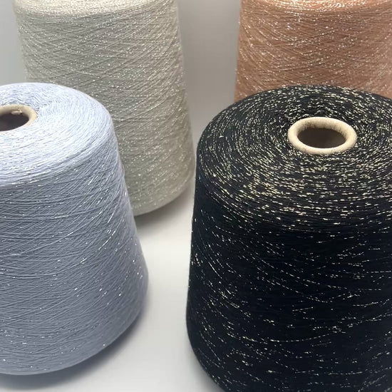 A luxurious cone of Pecci Filati SHIMMER yarn, a modern 50% Cotton, 25% Linen, 14% Polyester, and 12% Polyamide (Lurex) blend. The image showcases the refined metallic glow and delicate texture of this 3400m/100g Italian extrafine yarn, ideal for high-end blending. Authentic luxury fiber available at iDOKNiT.com.