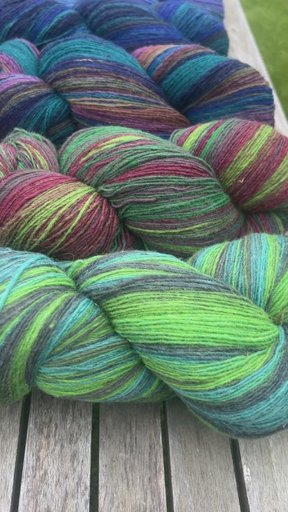 Small-batch dyed skeins of 100% Latvian Dark-Headed Sheep Wool in varied earth tones and vibrant multi-colors like Green-Brown striped 052. The rustic single-ply texture is shown in detail, including images of the sheep and the historic Paces Vilnas Fabrika origin. Available at iDOKNiT.com.