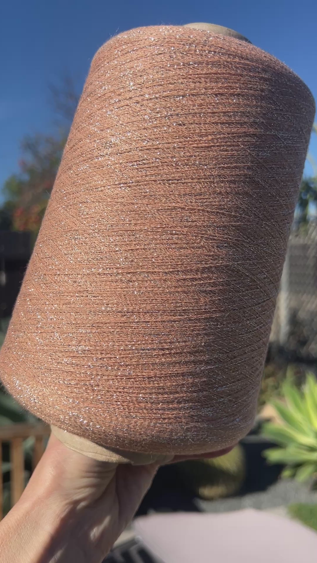 A luxurious cone of Pecci Filati SHIMMER yarn, a modern 50% Cotton, 25% Linen, 14% Polyester, and 12% Polyamide (Lurex) blend. The image showcases the refined metallic glow and delicate texture of this 3400m/100g Italian extrafine yarn, ideal for high-end blending. Authentic luxury fiber available at iDOKNiT.com.